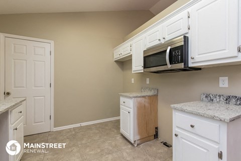 a kitchen with white cabinets and a microwave