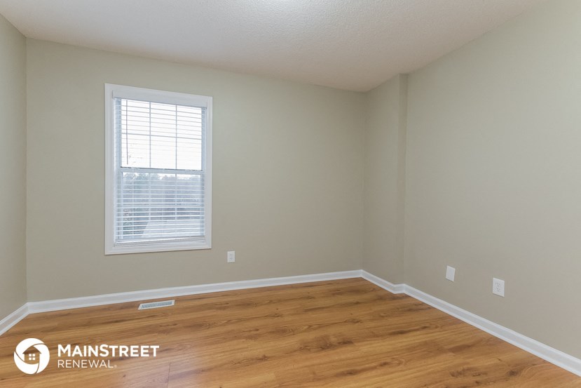 the interior of an empty room with wood floors and a window