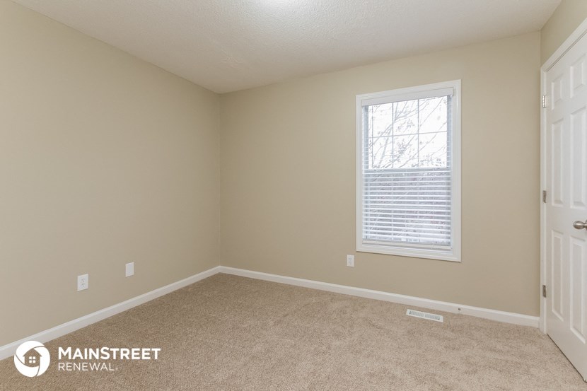 the upstairs bedroom with carpeted flooring and a window