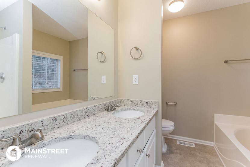 the master bathroom has dual sinks and a large mirror