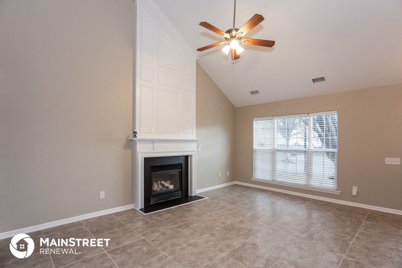 a living room with a fireplace and a ceiling fan
