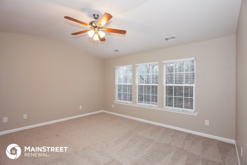 the master bedroom has a large window and a ceiling fan