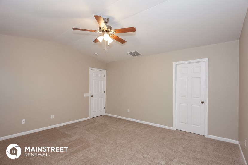 the master bedroom has a carpeted floor and a ceiling fan
