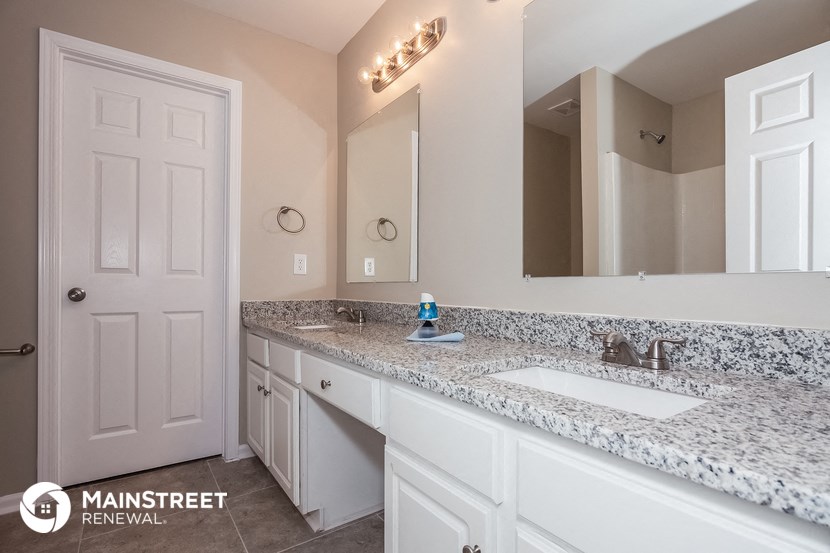 a bathroom with white cabinets and a sink and a mirror