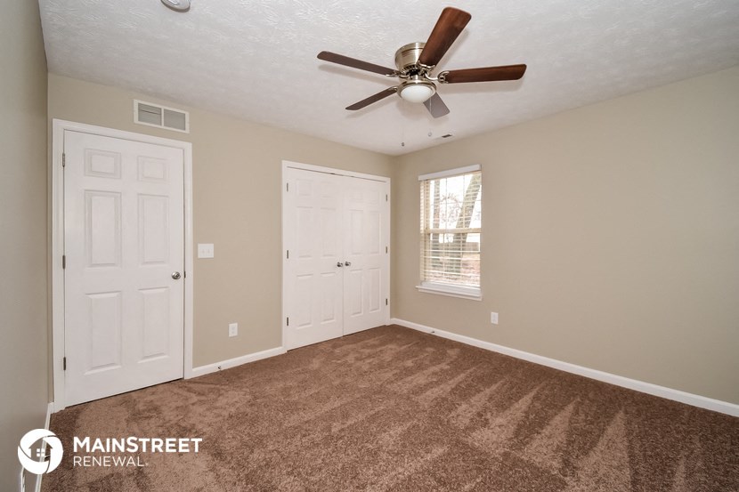 the master bedroom has a carpeted floor and a ceiling fan