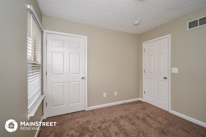 a bedroom with two doors and a carpeted floor