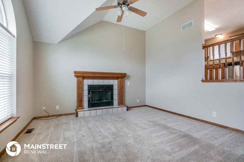 the living room with fireplace and ceiling fan