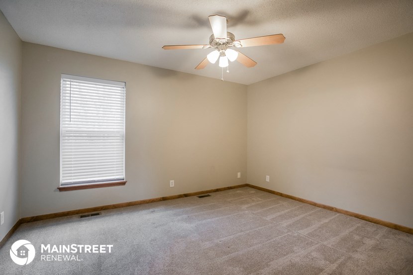 the spacious living room with carpet and a ceiling fan