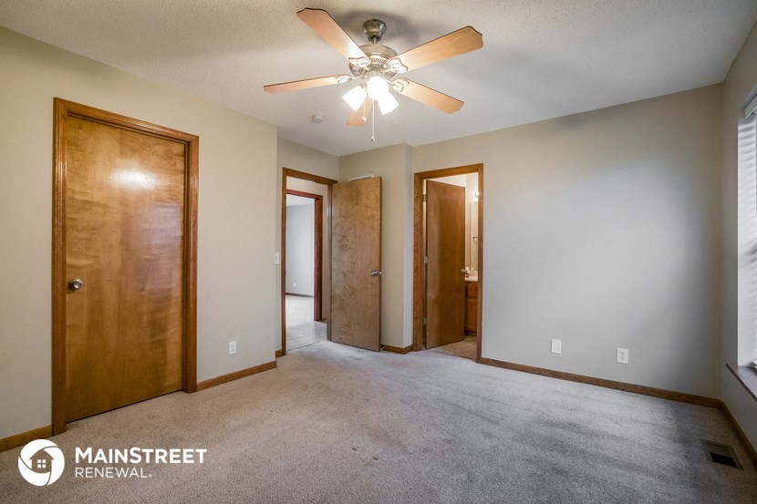 an empty room with a ceiling fan and two doors