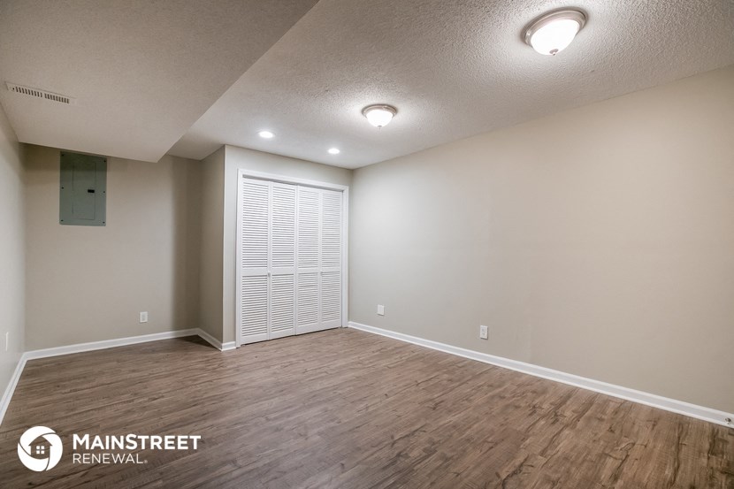 the spacious living room with wood flooring and white walls