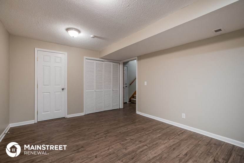 the spacious living room with a closet and a door to the hallway
