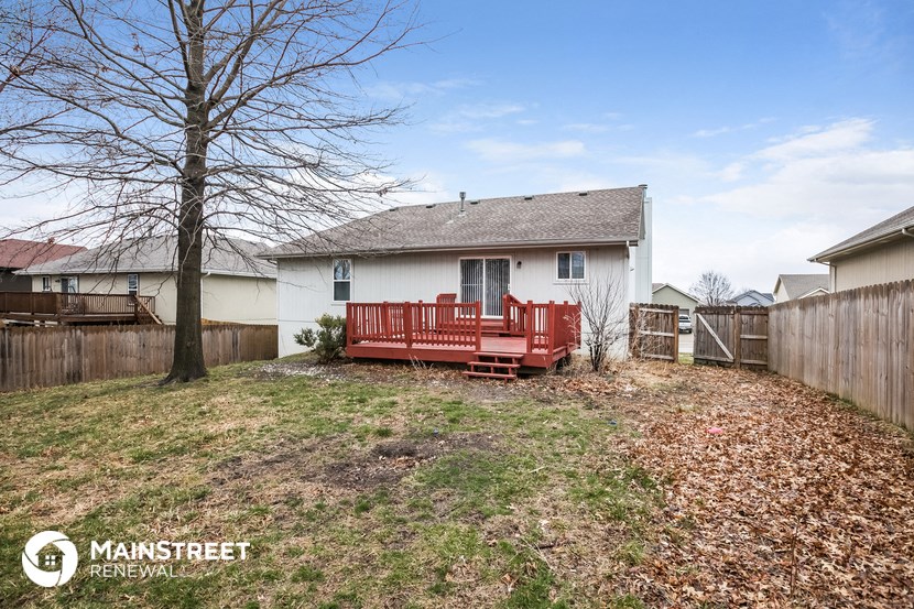 a backyard with a red bench in front of a house
