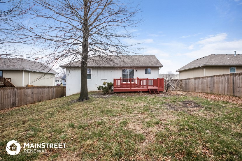 a backyard with a red deck and a tree