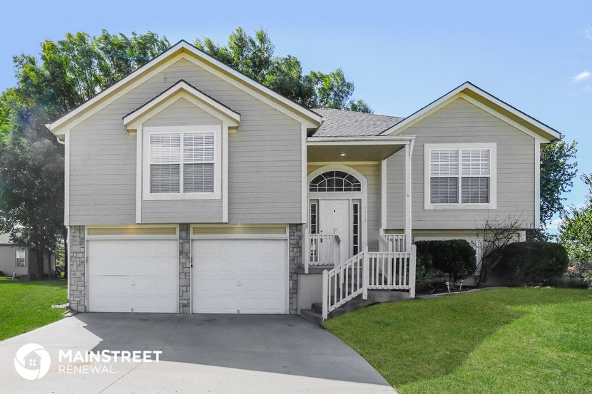 a gray house with white doors and a driveway