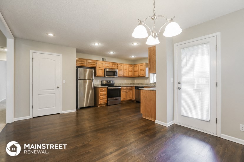 the kitchen and living room of an apartment with wooden cabinets and stainless steel appliances