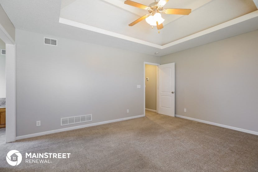 the spacious living room with ceiling fan and carpeting