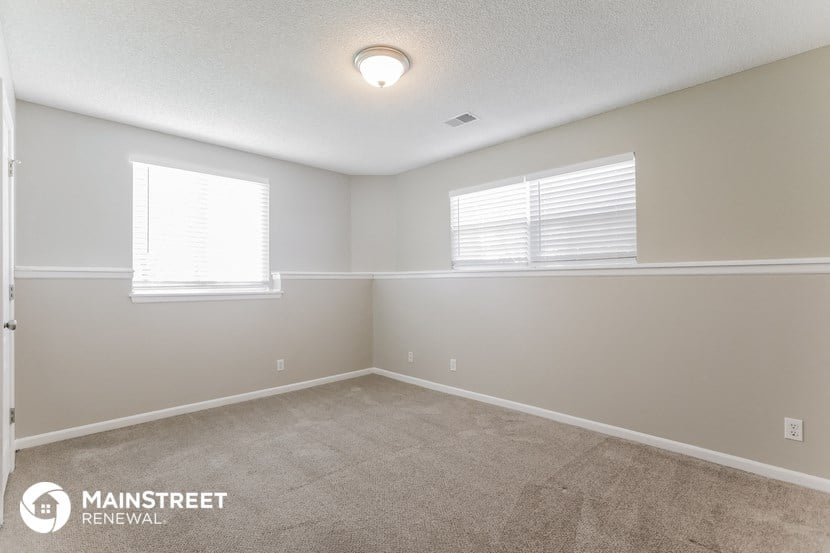 the spacious living room with carpet and two windows