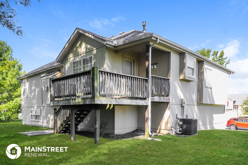 a white house with a deck and a car garage