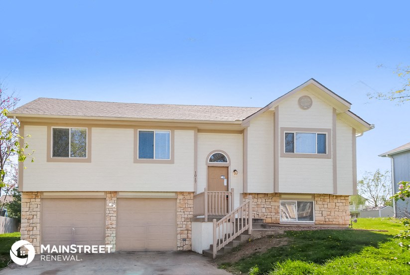 a beige house with a front porch and a staircase