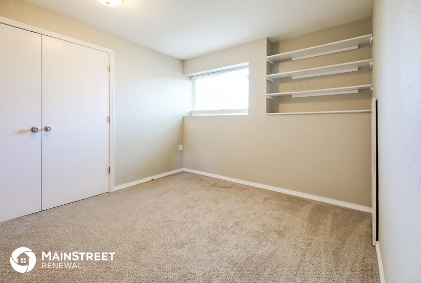 a bedroom with a closet and shelves and a window