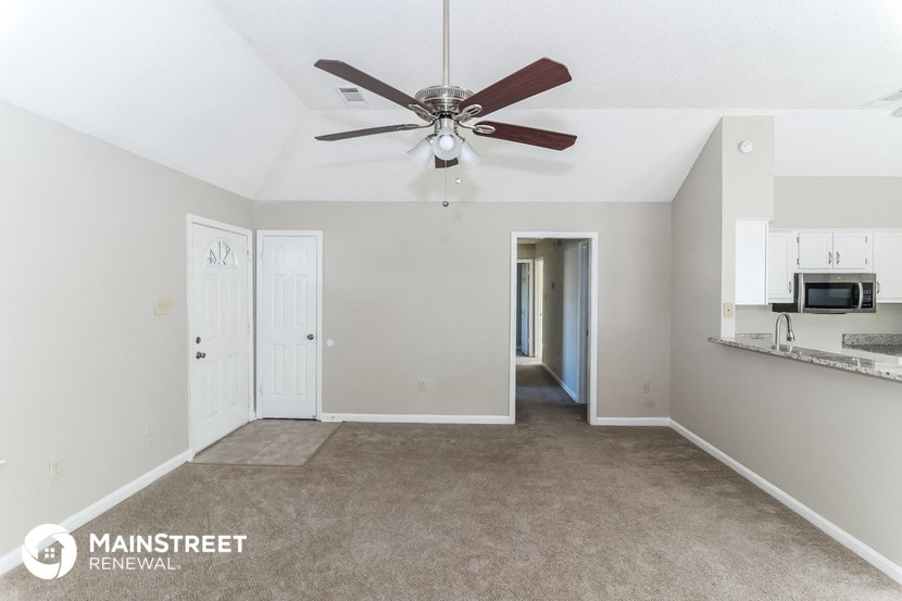 the living room is spacious and has a ceiling fan