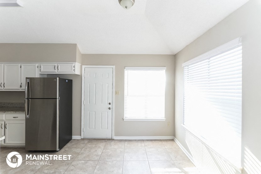 an empty kitchen with a refrigerator and a window
