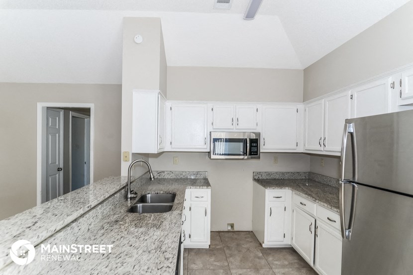 a kitchen with white cabinets and granite counter tops