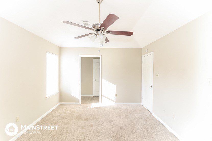 the master bedroom has a ceiling fan and a carpeted floor