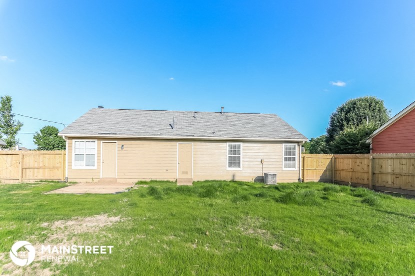 the backyard of a small house with a yard and a fence