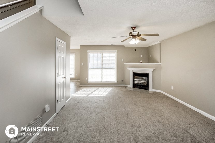an empty living room with a ceiling fan and a fireplace