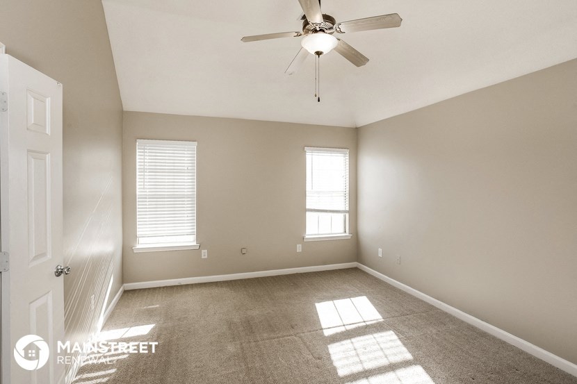 the spacious living room with ceiling fan and carpet
