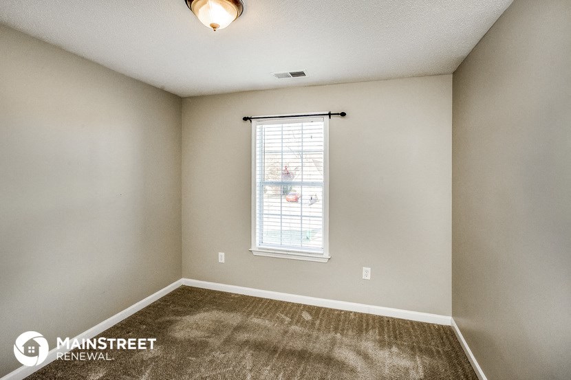 the living room of an empty home with carpet and a window