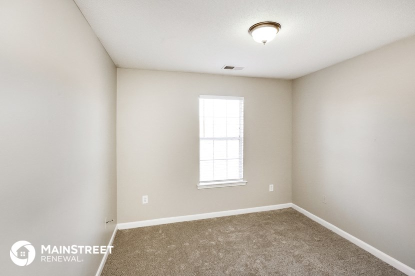 the spacious living room with carpeted flooring and a window