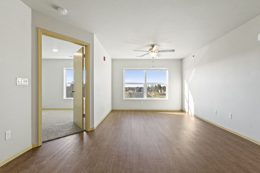 an empty living room with wood flooring and a ceiling fan