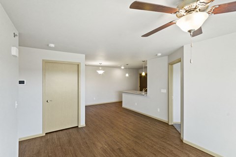 a living room with a ceiling fan and a door to a kitchen