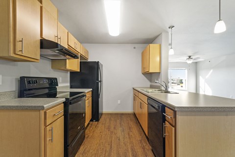 an empty kitchen with wooden cabinets and black appliances