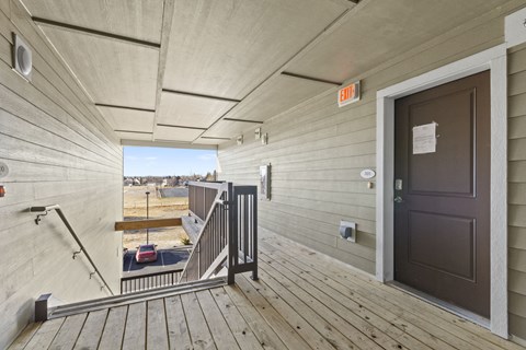 the front door of a home with a porch and a stairway with a window