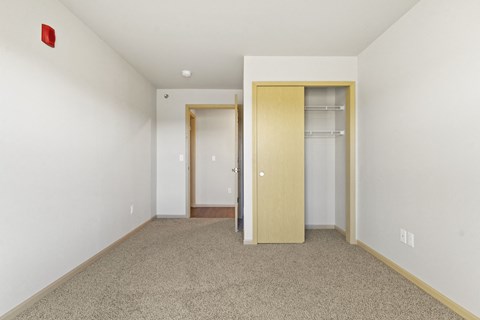 a bedroom with a carpeted floor and a door to a closet