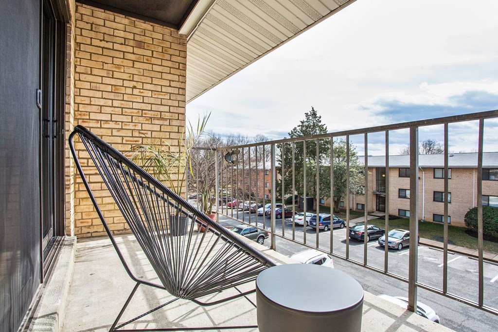 a balcony with a chair and a view of a parking lot
