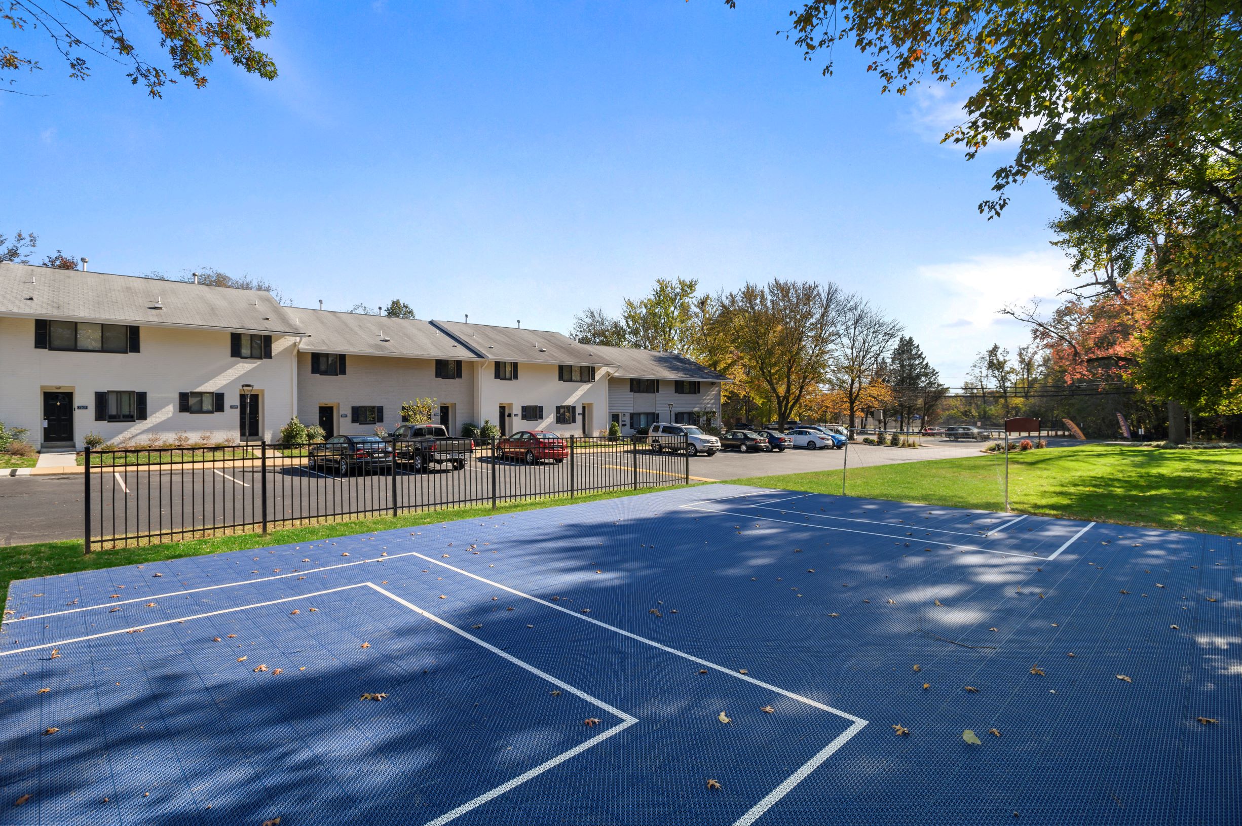a basketball court in front of a house with a parking lot