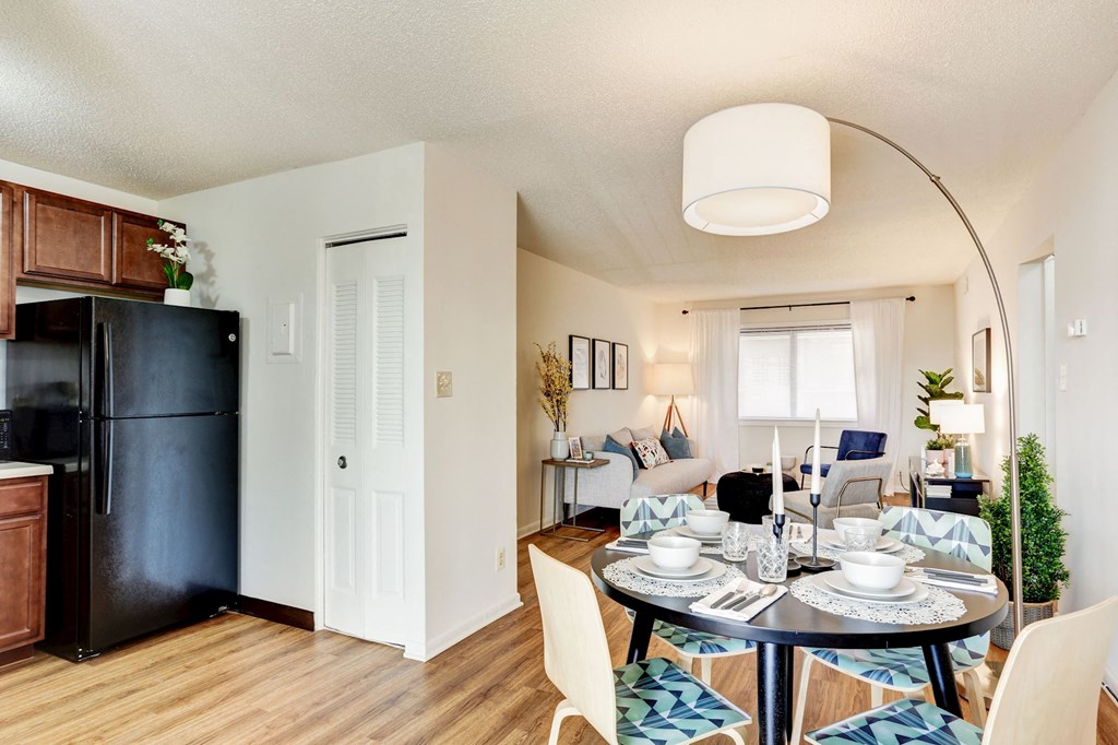 a living room and dining room with a table and a refrigerator