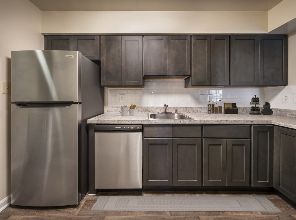 a kitchen with dark cabinets and a stainless steel refrigerator