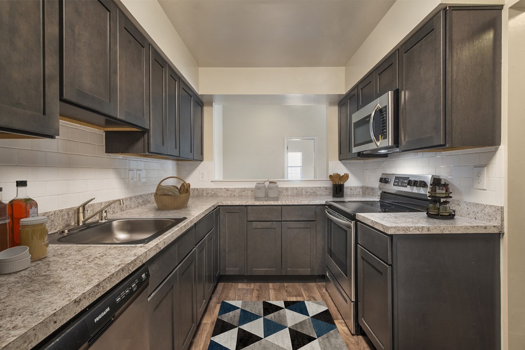 a kitchen with dark wood cabinets and granite counter tops and a sink