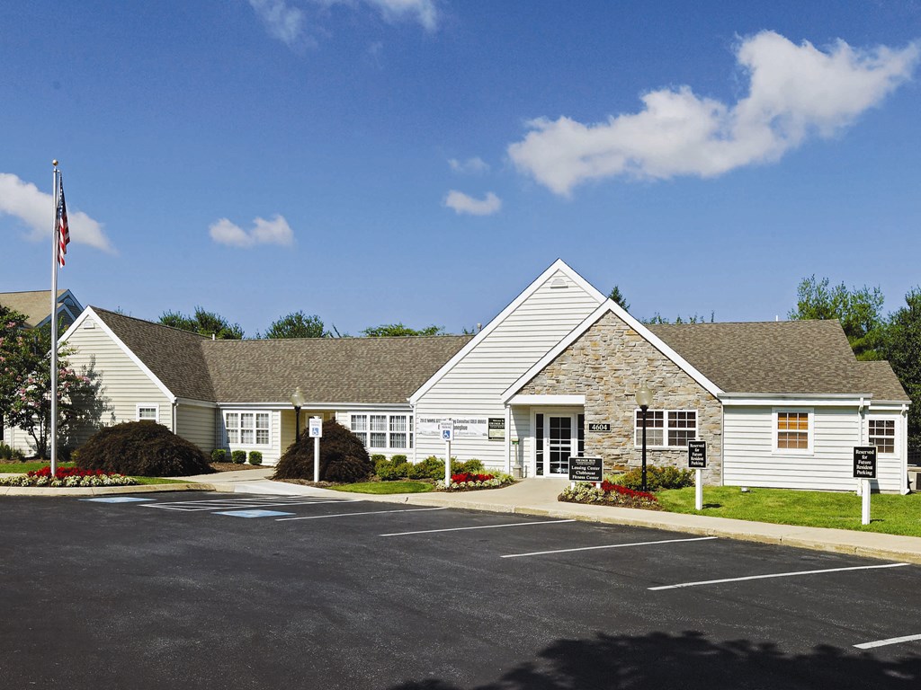 the front of a white house with a flag and a parking lot