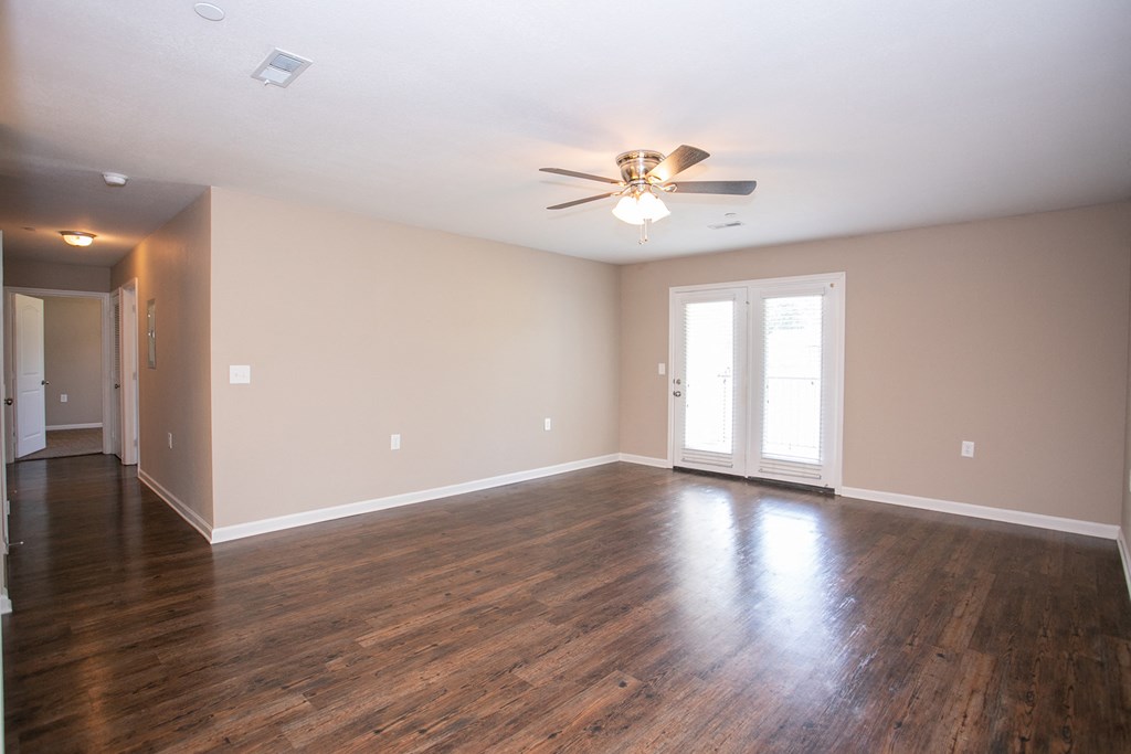 an empty living room with wood floors and a ceiling fan