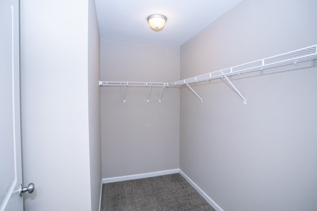 an empty closet with a white wall and a white closet door with a hanging rack