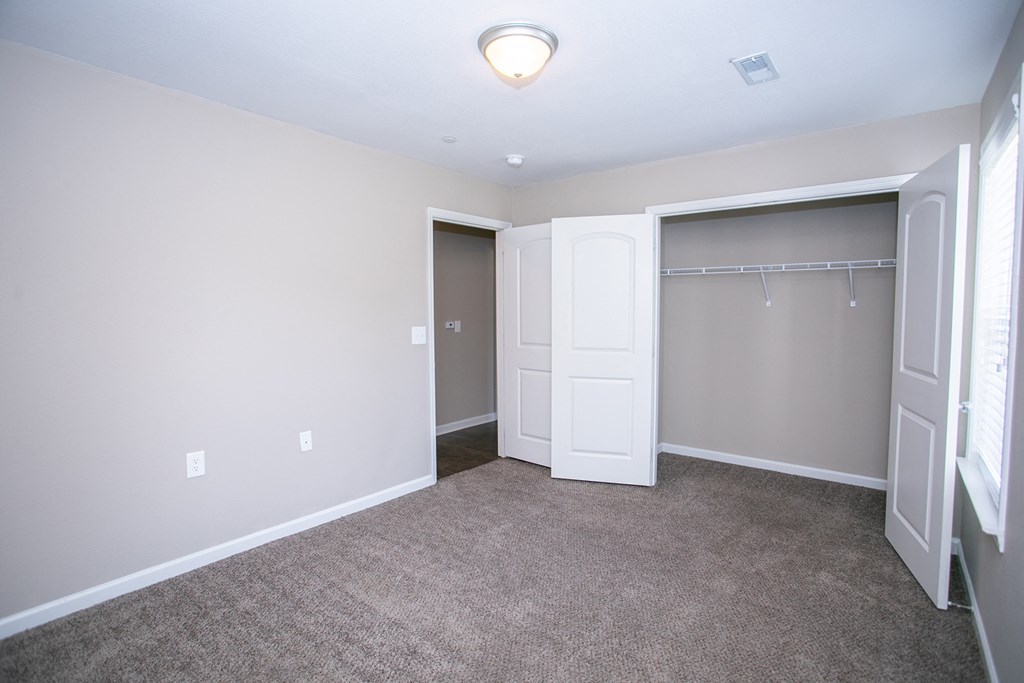 an empty bedroom with a closet and a mirrored closet door