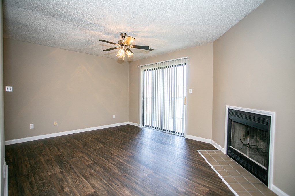 an empty living room with a fireplace and a ceiling fan