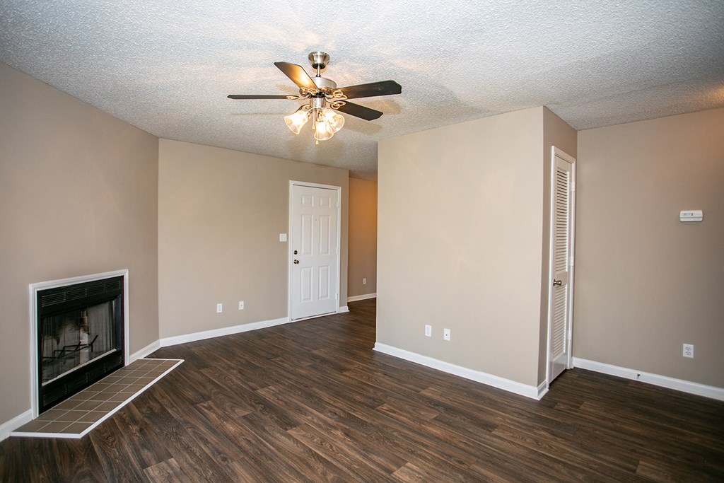 an empty living room with a fireplace and a ceiling fan