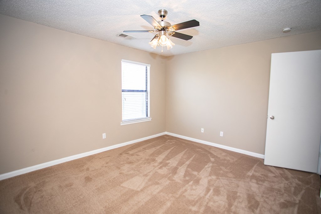an empty living room with carpet and a ceiling fan